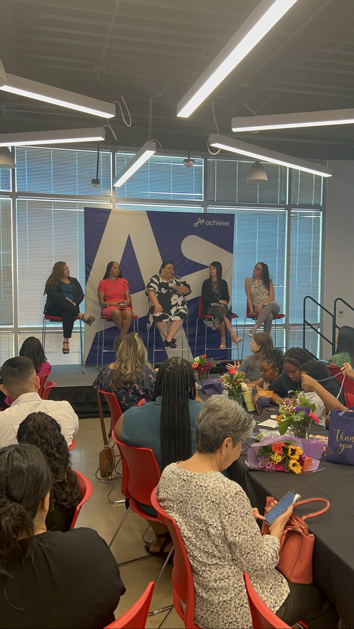 Five panelists seated on stage at the 2025 Inspired LeadHER graduation event with the cohort audience visible.
